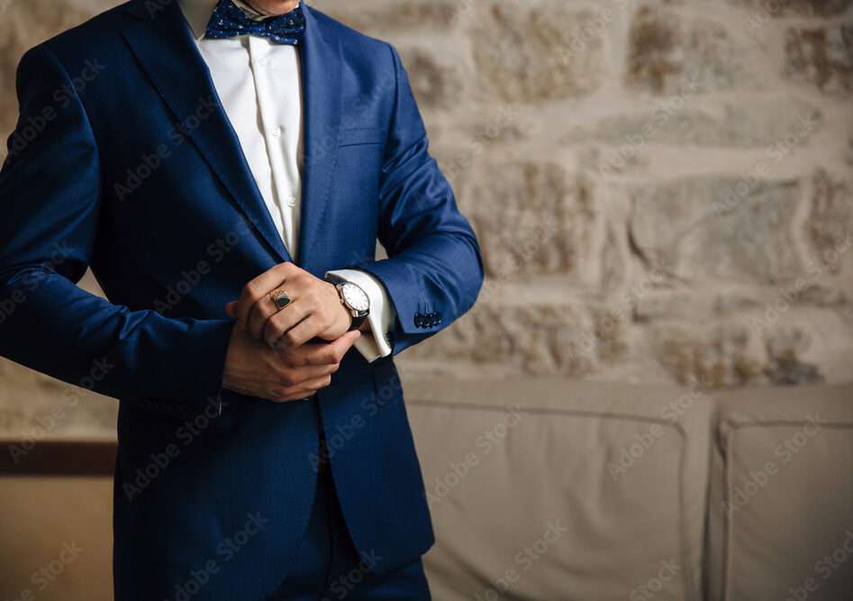 a-close-up-of-a-cropped-frame-of-a-man-in-an-expensive-classic-costume-looks-at-his-watch-the-businessman-is-in-a-hurry-and-looks-at-the-time-a-handsome-man-with-a-precious-watch-and-a-gold-ring-stockpack-adobe-stock | WEDISTRY BLOG A close-up of a cropped frame of a man in a traditional wedding tux looks at his watch. The businessman is in a hurry and looks at the time. A handsome man with a precious watch and a gold ring.
